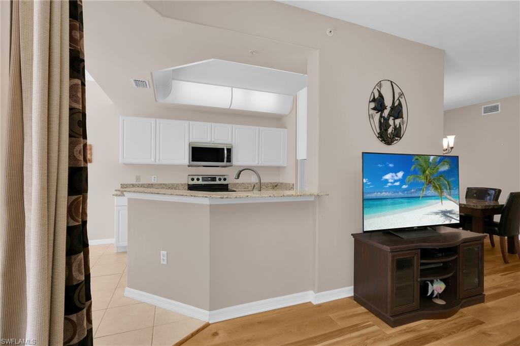 1435 Tiffany Lane, Unit 302 Naples, FL 34105 - Photo 11 of 36 a living room with stainless steel appliances kitchen island furniture and a flat screen tv