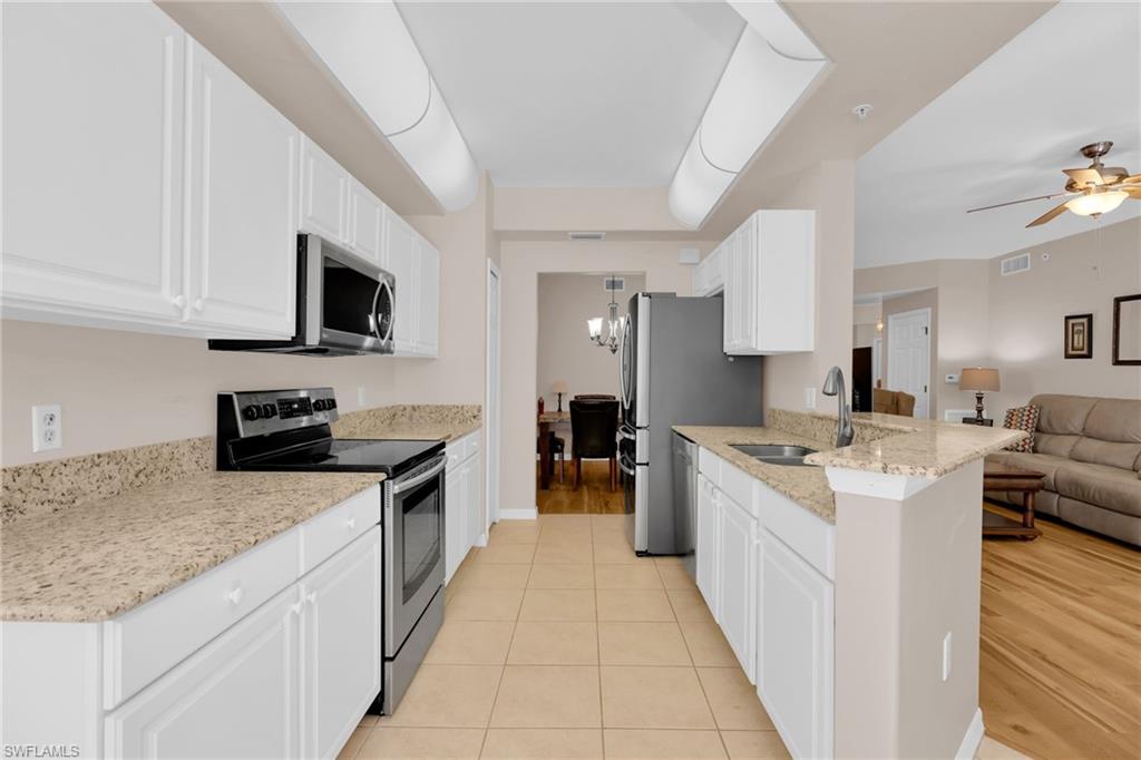 1435 Tiffany Lane, Unit 302 Naples, FL 34105 - Photo 8 of 36 a large kitchen with a stove top oven a sink a counter space and cabinets