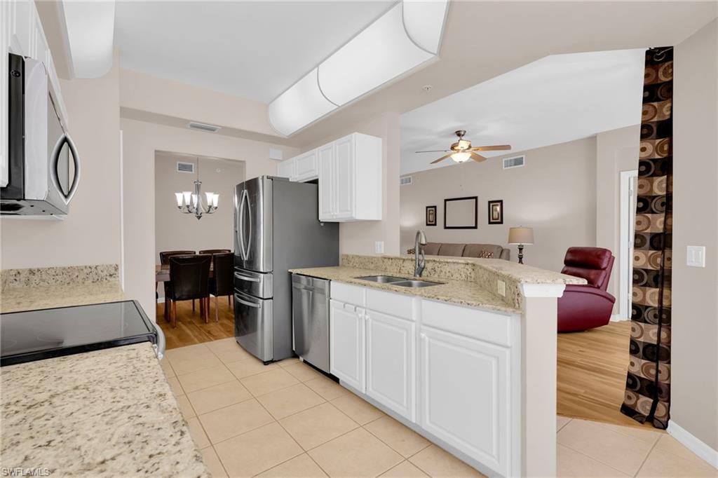 1435 Tiffany Lane, Unit 302 Naples, FL 34105 - Photo 9 of 36 a kitchen with stainless steel appliances kitchen island granite countertop a sink and cabinets