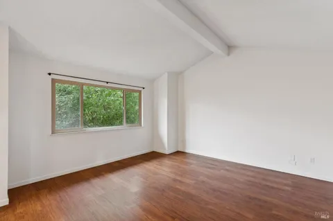 a view of a livingroom with wooden floor and a bathroom