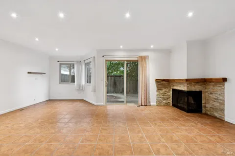 an empty room with windows and fireplace