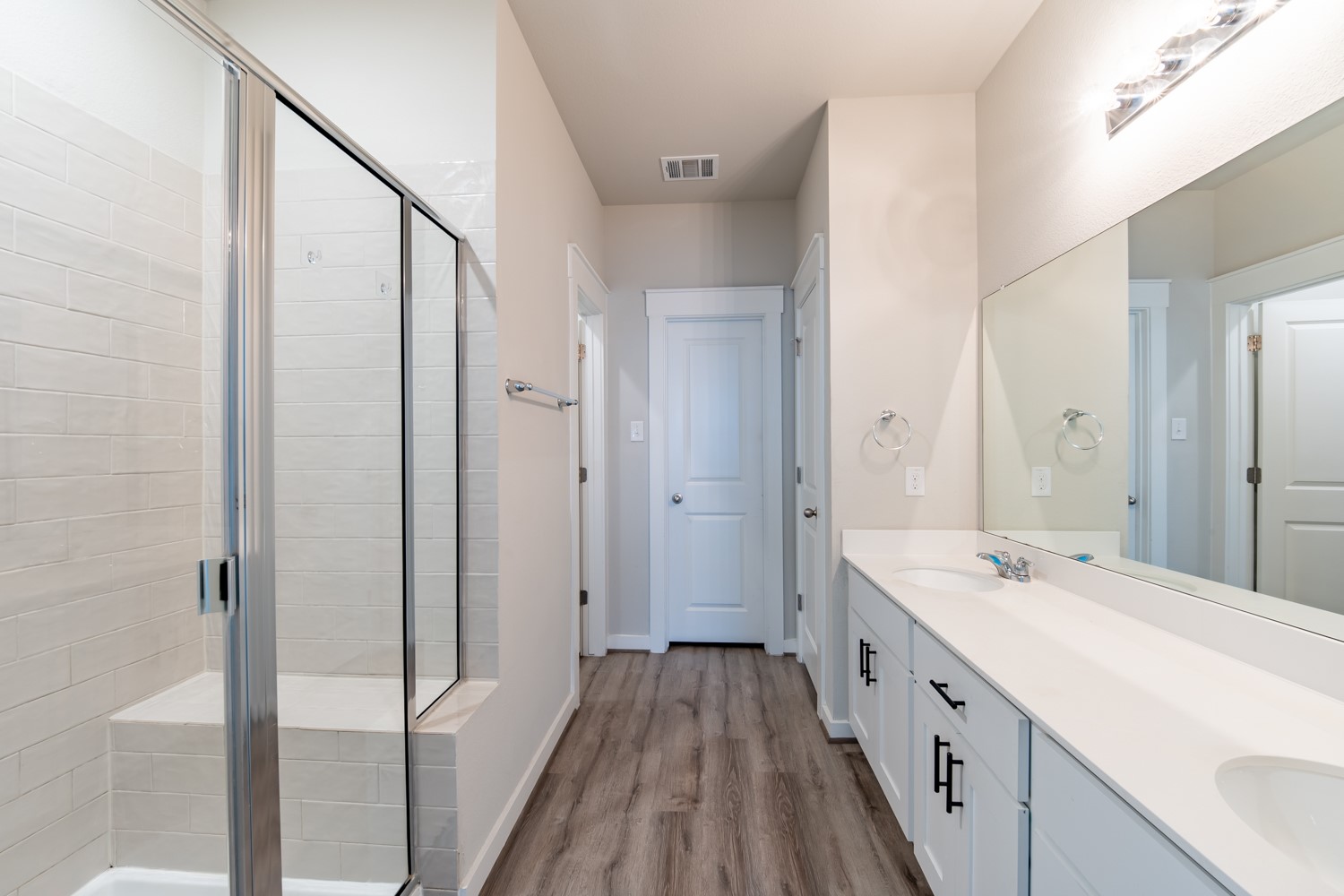 147 Waterside Road, Unit A Buda, TX 78610 - Photo 16 of 27 A sleek, contemporary bathroom offers dual sinks, an expansive mirror, and a spacious glass-enclosed shower.
