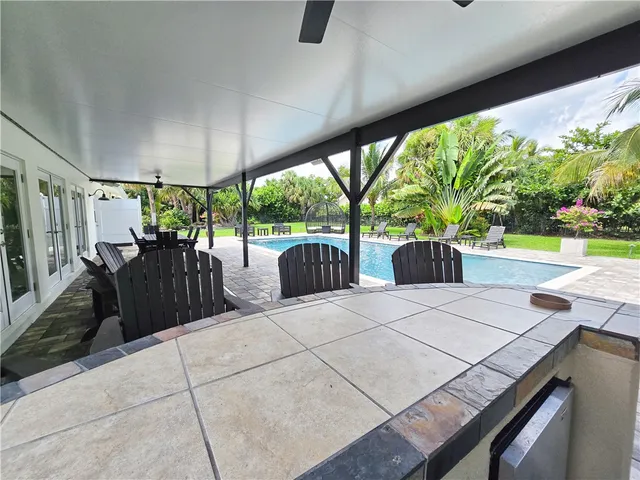 a view of a patio with table and chairs potted plants with floor to ceiling window