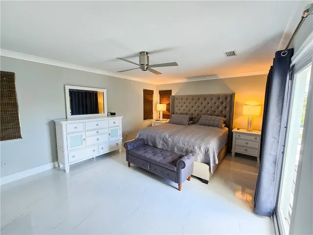 a spacious bedroom with a bed a couch and a flat tv screen on dresser