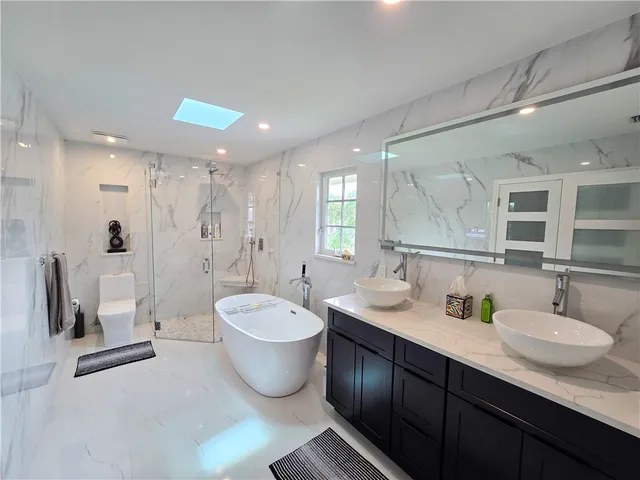 a bathroom with a double vanity sink a toilet a mirror and shower