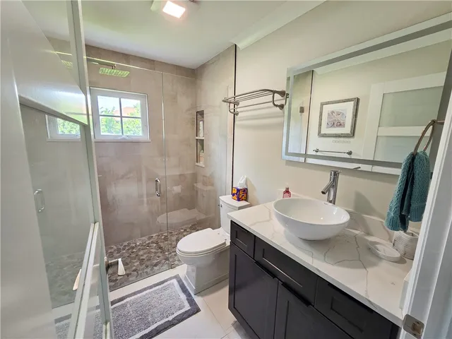 a bathroom with a sink a toilet a mirror and shower