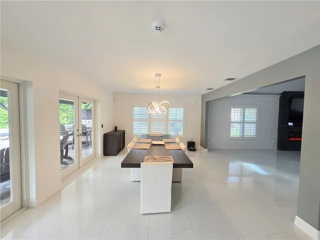 a large living room with furniture a chandelier and a large window
