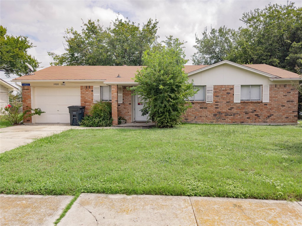 Single story home with a garage, a front yard, brick siding, and concrete driveway