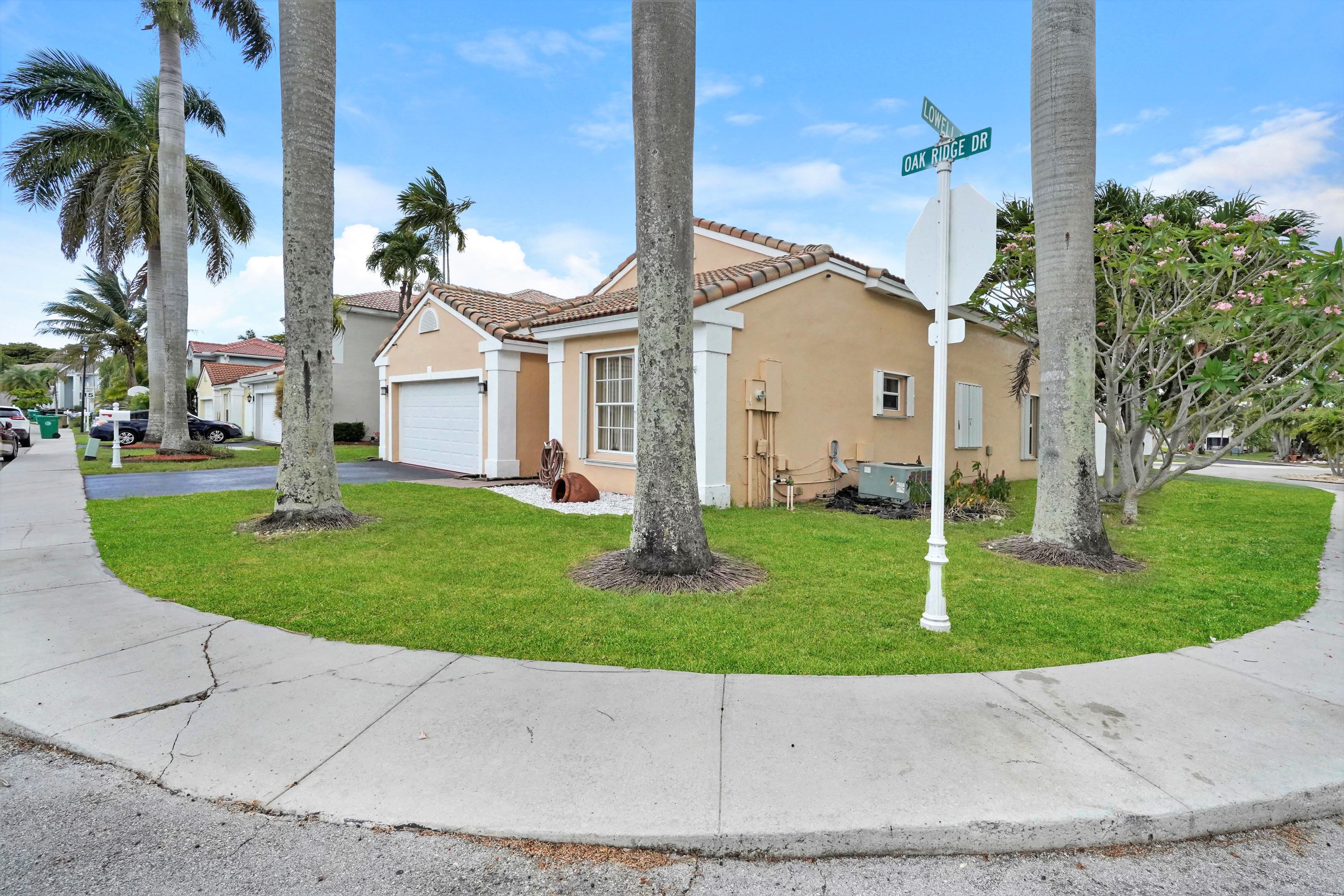 14001 Oak Ridge Drive Davie, FL 33325 - Photo 2 of 41 a front view of a house with a garden and trees