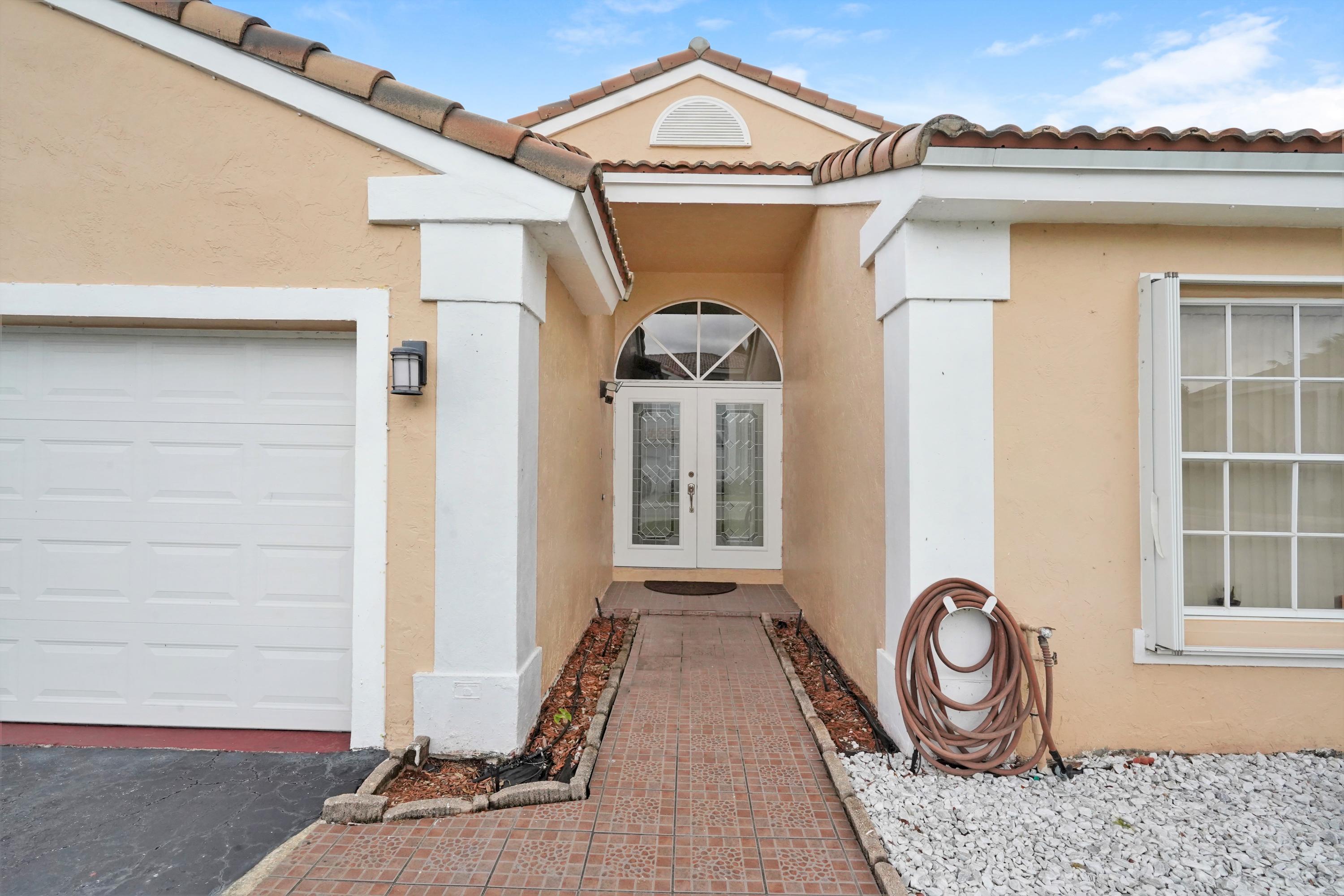 14001 Oak Ridge Drive Davie, FL 33325 - Photo 4 of 41 a front view of a house with a garden