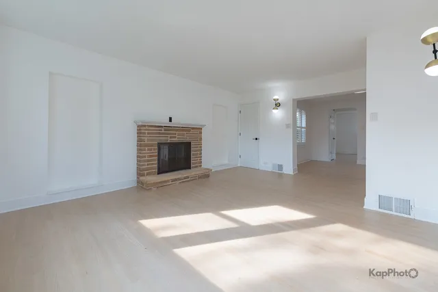 a view of an empty room with a fireplace and a window