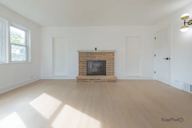 an empty room with windows and fireplace