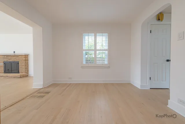 a view of an empty room with a window and fireplace