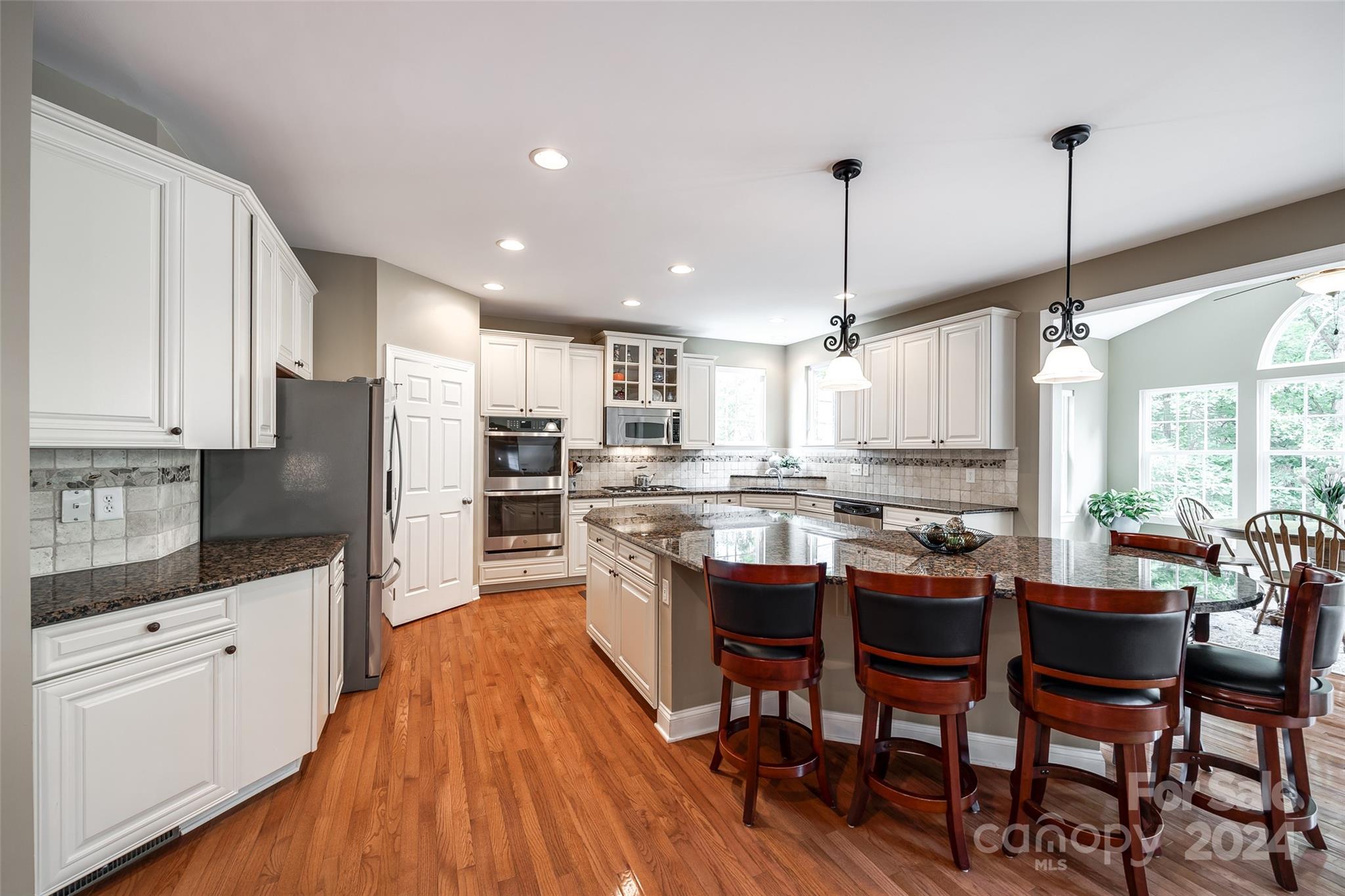 352 Calming Way Tega Cay, SC 29708 - Photo 15 of 48 a kitchen with stainless steel appliances kitchen island granite countertop a table chairs sink and cabinets