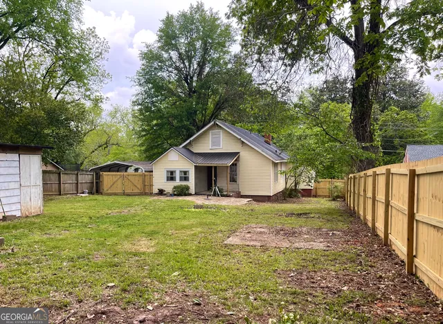 a view of a house with yard and large trees