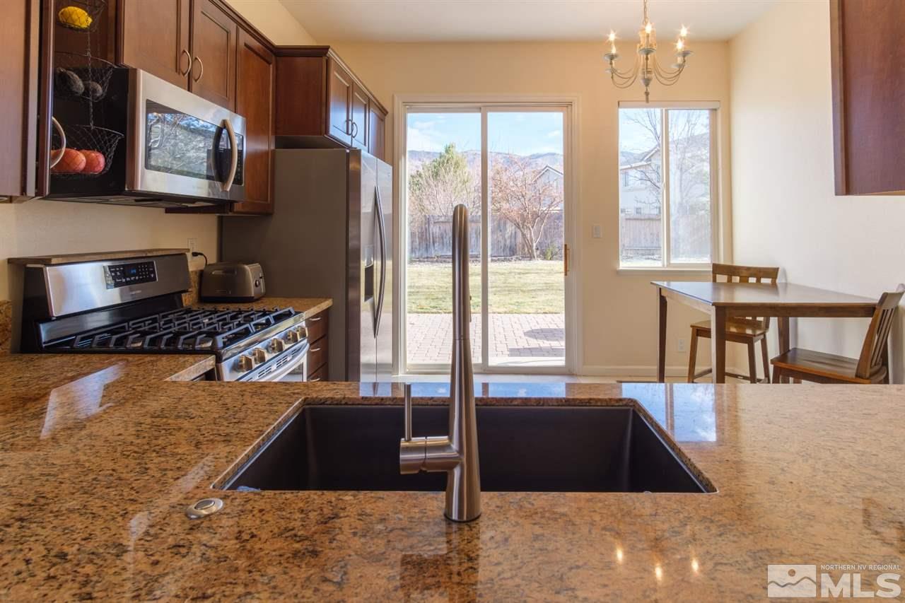 2220 Hampton Park Court Reno, NV 89521 - Photo 8 of 22 a kitchen with stainless steel appliances granite countertop a stove a refrigerator a sink a dining table and chairs with wooden floor