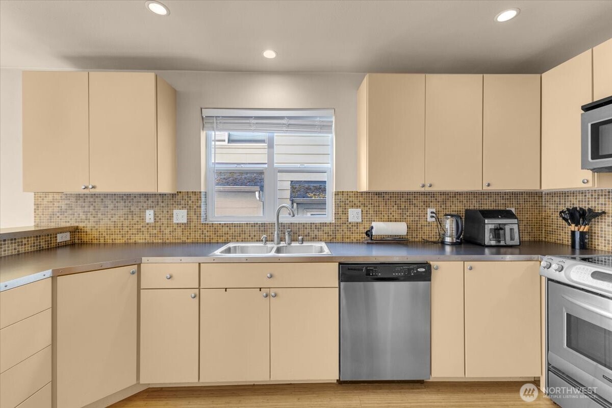 1719 Southwest Henderson Street Seattle, WA 98106 - Photo 5 of 22 a kitchen with granite countertop white cabinets sink and stainless steel appliances