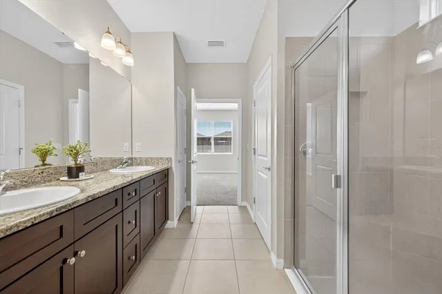 a spacious bathroom with a granite countertop sink a mirror and a shower