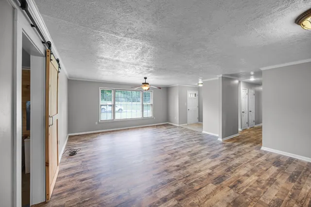 a view of an empty room with wooden floor and a window
