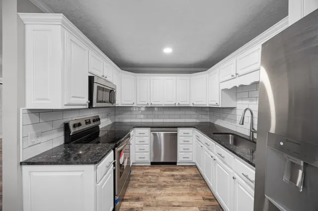 a kitchen with stainless steel appliances granite countertop a sink and dishwasher a stove top oven with wooden floor