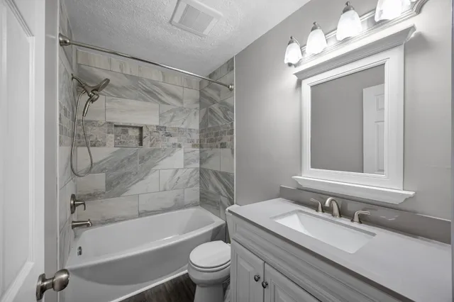 a bathroom with a bathtub shower sink vanity mirror and toilet