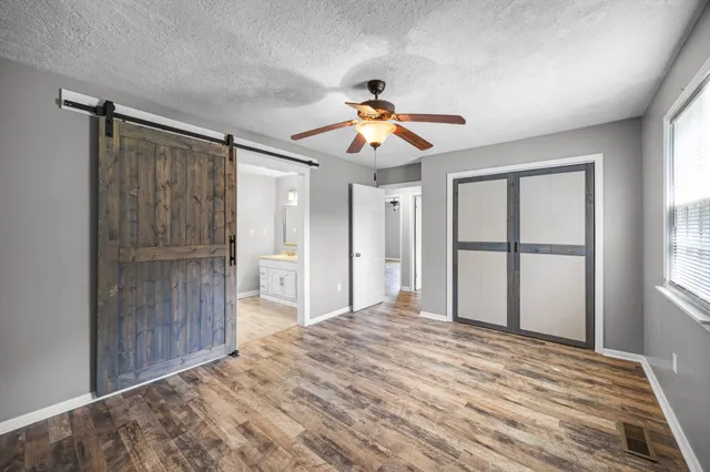 a view of a bedroom with wooden floor and a ceiling fan