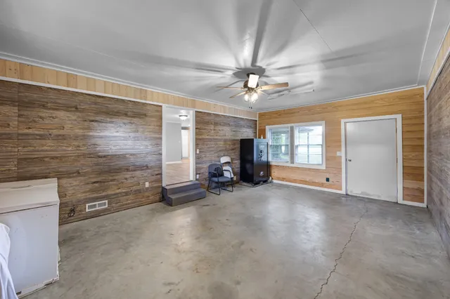 a view of a livingroom with a fireplace a chandelier fan and windows