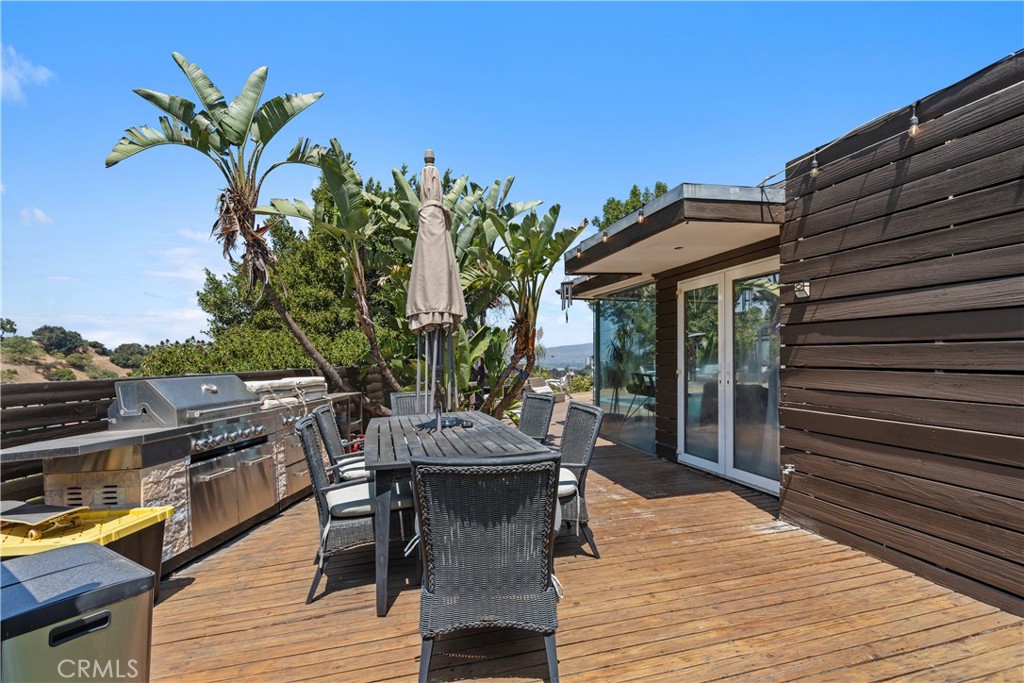7241 Woodrow Wilson Drive Los Angeles, CA 90068 - Photo 24 of 43 a view of a roof deck with table and chairs with wooden floor and plants