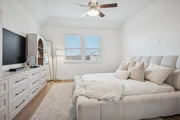a bedroom with a large bed and a flat tv screen on dresser