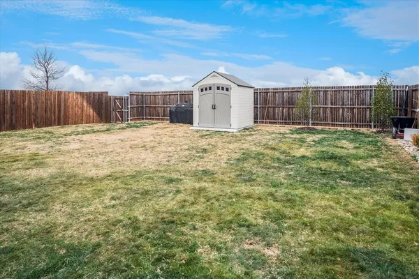 a view of a backyard with a barbeque and wooden fence
