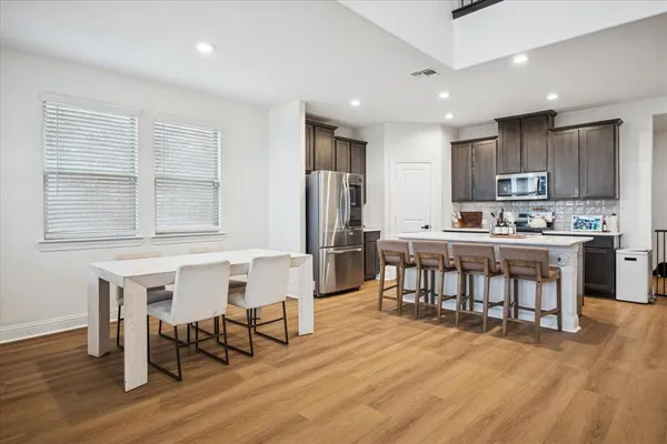 a kitchen with kitchen island a dining table chairs and white cabinets