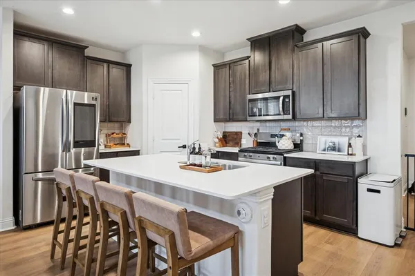 a kitchen with stainless steel appliances a sink stove refrigerator and cabinets