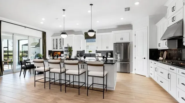 a kitchen with stainless steel appliances kitchen island granite countertop a table chairs and a stove