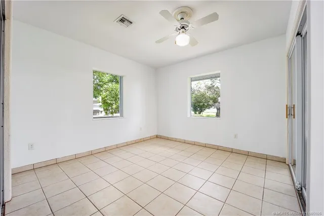 an empty room with windows and chandelier fan