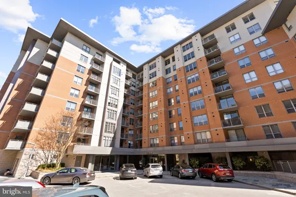 a front view of a building with lot of cars and trees