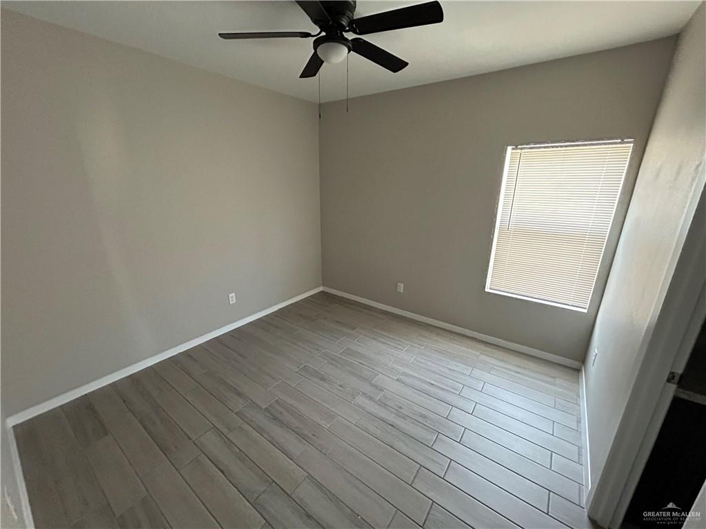 5705 Puffin Avenue, Unit 1 Mission, TX 78573 - Photo 12 of 16 an empty room with wooden floor fan and windows