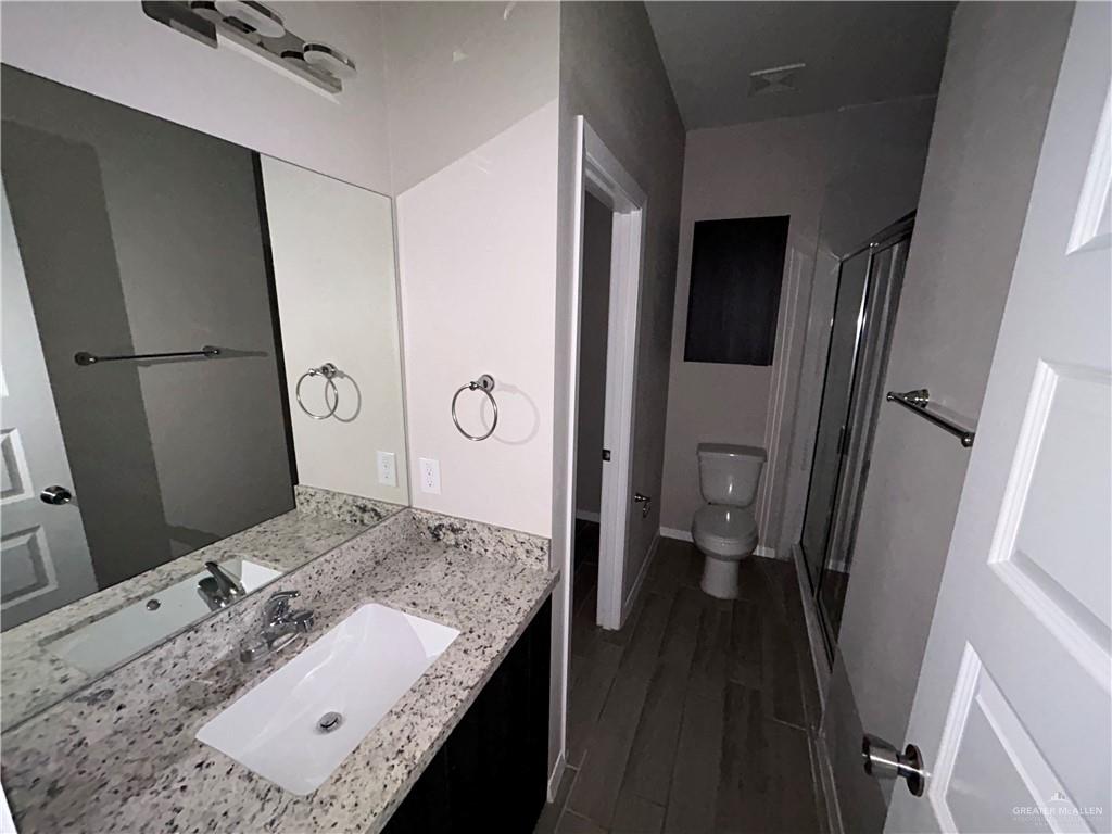 5705 Puffin Avenue, Unit 1 Mission, TX 78573 - Photo 13 of 16 a bathroom with a granite countertop sink a mirror and a toilet