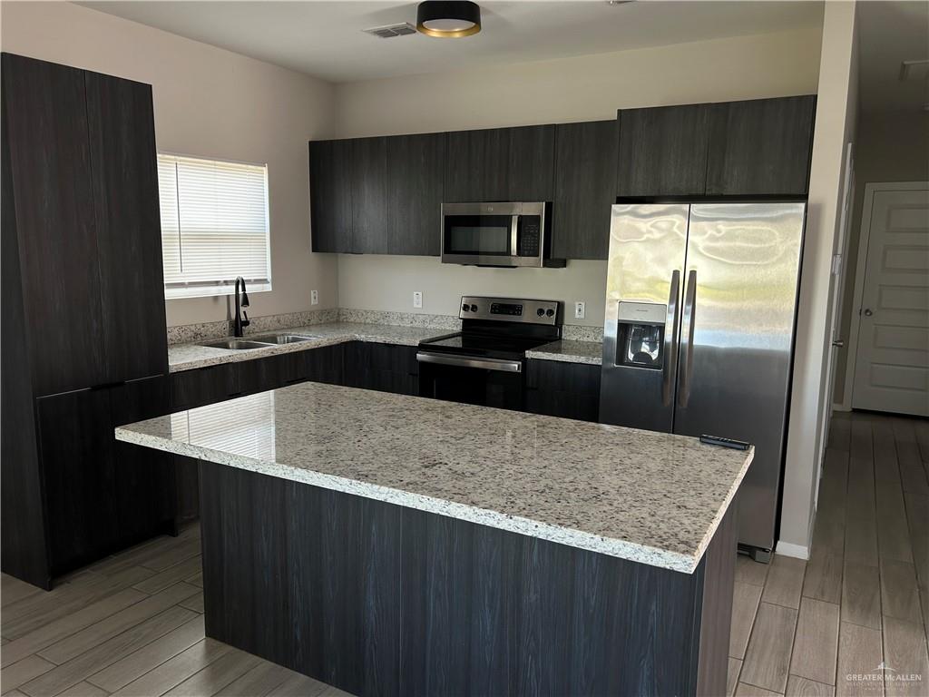 5705 Puffin Avenue, Unit 1 Mission, TX 78573 - Photo 5 of 16 a kitchen with a sink a microwave a refrigerator and cabinets