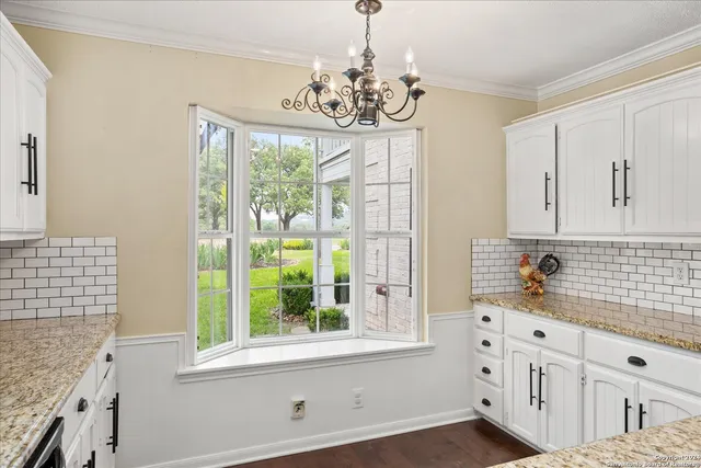 a kitchen with stainless steel appliances chandelier cabinets and window