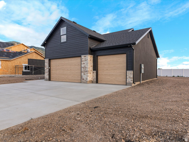 1267 West 2350 South Perry, UT 84302 - Photo 4 of 35 Two-car garage with wood-finish doors and stone accents