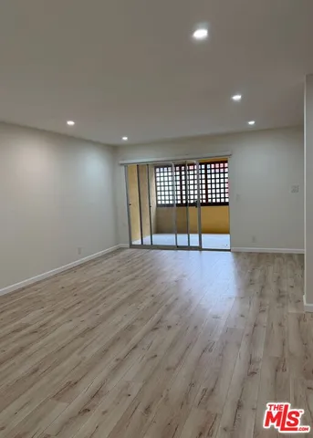 an empty room with wooden floor and glass door