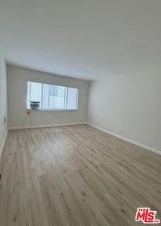 an empty room with wooden floor and window