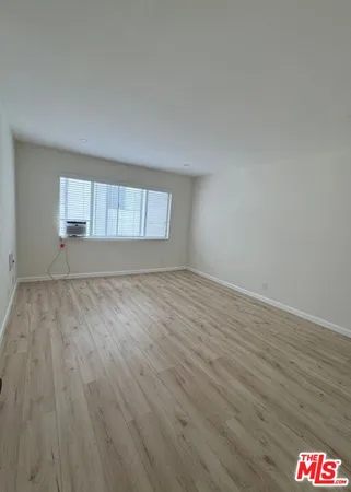 an empty room with wooden floor and window