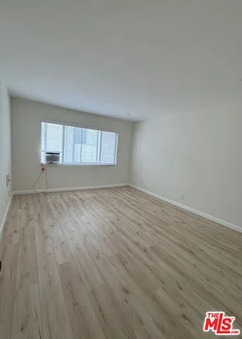 an empty room with wooden floor and window