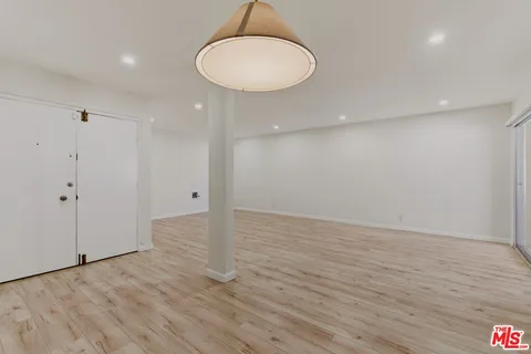 a view of an empty room with wooden floor and a painting