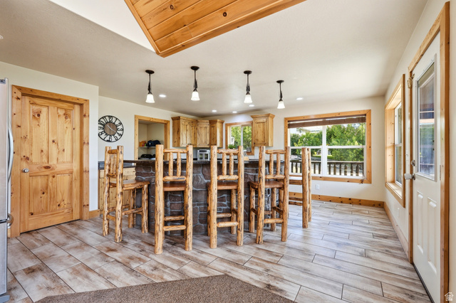 306 Spring Road Preston, ID 83263 - Photo 10 of 55 Open-concept kitchen featuring wood-finish flooring, a stone-clad island with seating, pendant lighting, wood cabinetry, and extensive natural light from multiple windows