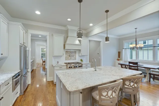 a kitchen with stainless steel appliances granite countertop a stove a refrigerator a oven a sink with a dining table and chairs