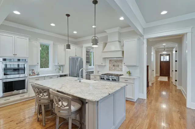 a kitchen with stainless steel appliances granite countertop a kitchen island a stove a table and chairs