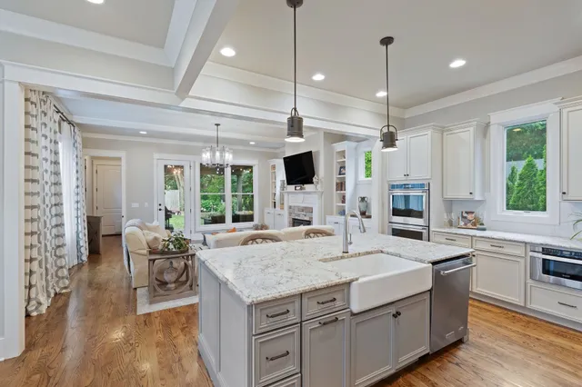 a kitchen with a stove a refrigerator a oven and a dining table with wooden floor