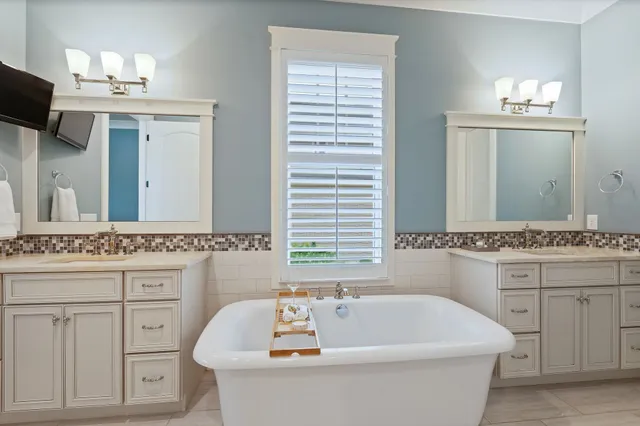 a bathroom with a tub a double vanity sink and mirror